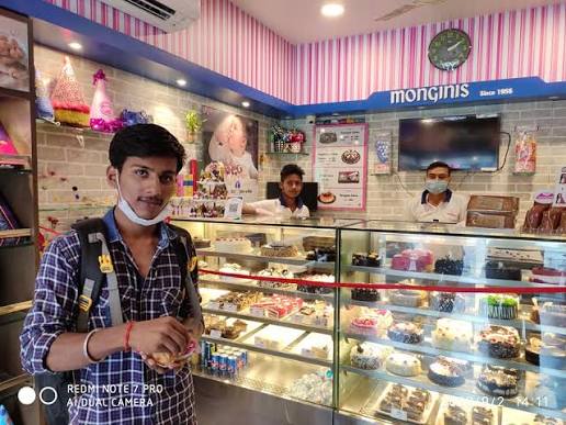 Customer standing beside a lit cake display with staff behind the counter