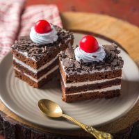 Slice of black forest pastry with cream and cherry