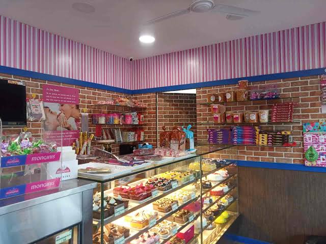 Pink-striped cake shop with shelves of gift items and a display chiller